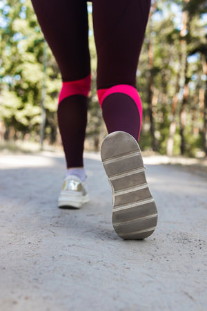 Close-up of female feet in sportswear running in forest