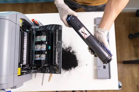 printer repair technician. A male handyman inspects a printer before starting repairs at the service...