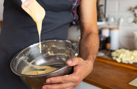 Close-up of a man mixing dough in a bowl at home