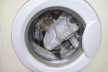 white sneakers in laundry machine. Washing machine in the process, wash clothes in the washing machine.の写真素材