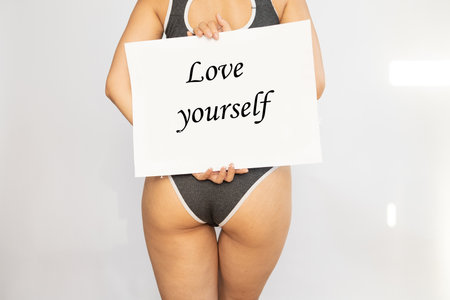 happy plus size girl holding placard with love your body lettering isolated on white, body positive concept.の写真素材
