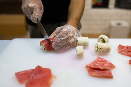 Sushi roll making at home, cutting roll with avocado and salmon, home made sushi, selective focusの写真素材