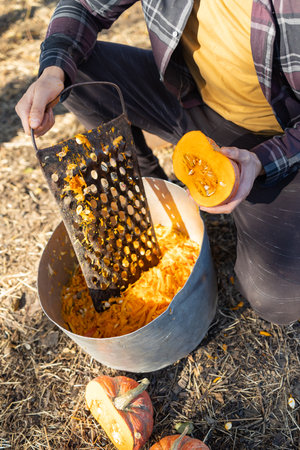 man rubs the pumpkin on a metal grater. Cooking. Vegan and vegetarian food. Raw food.の写真素材