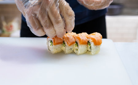 Close up of a chef preparing a sushi roll in a restaurant kitchenの写真素材