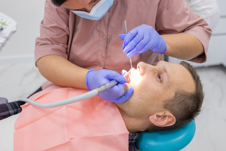 Side view of female dentist examining male patient with tools in dental clinicの写真素材