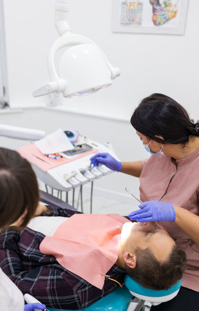 Closeup of a dentist and assistant treating a patient in dental clinic.