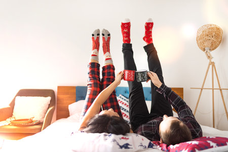 Happy family in Christmas socks sitting on the bed and holding a cupの写真素材