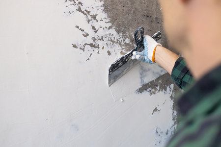 Worker painting the wall with a spatula, close-upの写真素材