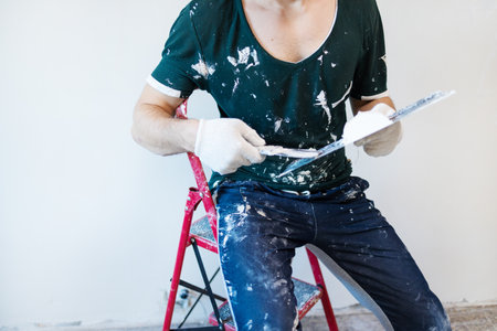 Hands man plasterer construction worker at work with trowel, plastering a wall, closeup.の写真素材