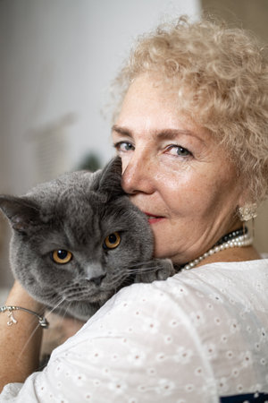 Portrait of a beautiful senior woman with her cat at home.の写真素材