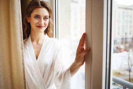 Beautiful bride in white wedding dress posing in her room at homeの写真素材
