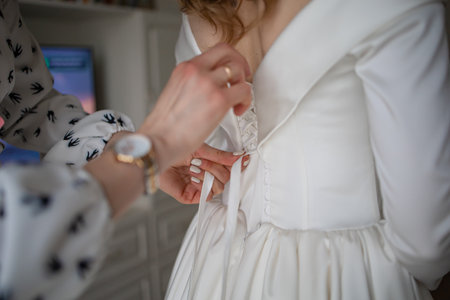 A gorgeous blonde bride in a white luxurious dress is preparing for the wedding. Morning preparation. A woman puts on a dress.の写真素材