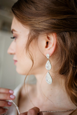 Beautiful woman wearing earrings and necklace on her wedding day. Close up.の写真素材