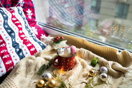 Cozy home interior with a cup of hot drink and Christmas decorations on the windowsill