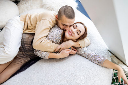 Couple in love on the bed at home. Young man and woman huggingの写真素材