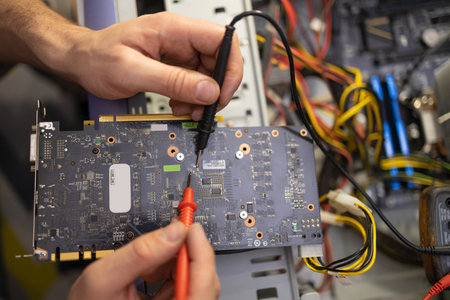 Close-up image of technician man hand measuring electrical voltage of computer mainboard by using digital multimeter. Maintenance and repair computer hardware service concept.の写真素材