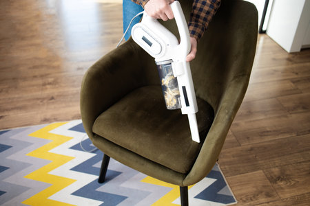 Close-up of a man cleaning the living room with a vacuum cleanerの写真素材