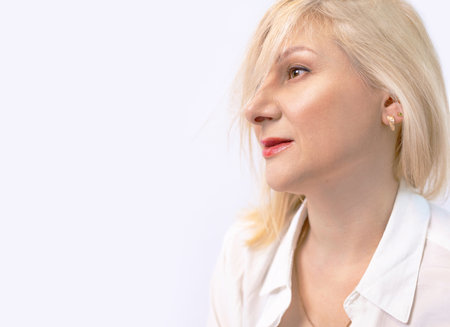Closeup portrait of a beautiful middle aged woman with blond hair on white background