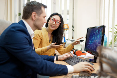 Asian business woman sharing her expertise with her colleague as they collaborate on a project using...