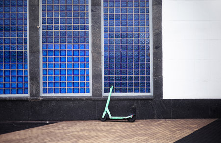 Green scooter in front of the blue window of a modern building