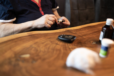 Senior woman using sanitizer for blood sugar testing at home.の写真素材