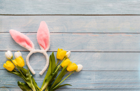 Easter bunny ears with tulips on a blue wooden background.の写真素材