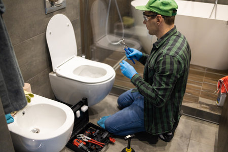 Plumber repairing toilet bowl in the bathroom at the repair shop.の写真素材