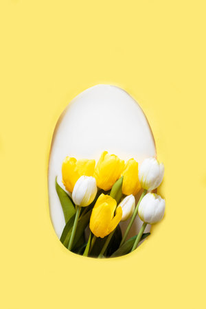 Creative Easter layout with tulips flowers on yellow paper background. Spring nature Easter holiday minimal concept. Egg shape flat lay.の写真素材