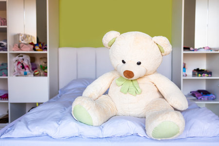 Cute teddy bear sitting on the bed in children's roomの写真素材