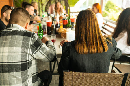 Back view of young people sitting at a table in a restaurant.の写真素材