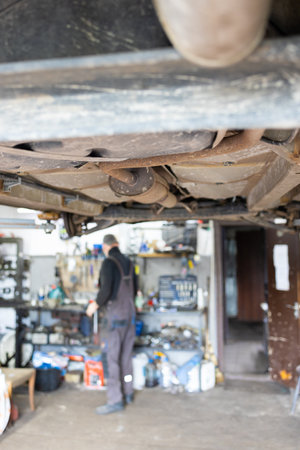 Auto mechanic repairing a car in auto repair shop, blurred background.の写真素材
