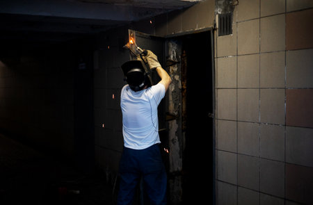 Welder in protective mask welding metal with torch in a construction site