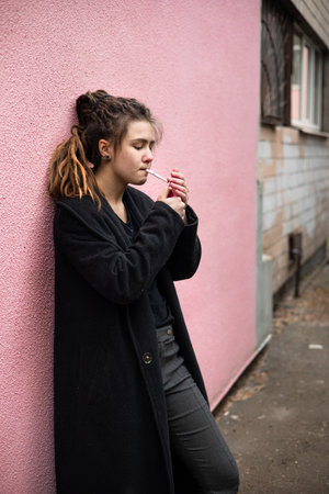 Portrait of a young woman smoking a cigarette in the street.の写真素材