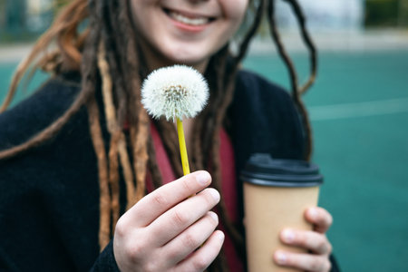Girl holding a dandelion flower outdoor. Happiness and environment. Feeling with nature. People in outdoor leisure activity alone. Spring and autumn concept season.の写真素材