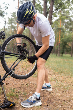 Cyclist adjusting wheel of his bicycle during obstacle course in forestの写真素材