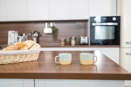 Coffee mugs and croissants on wooden table in kitchenの写真素材