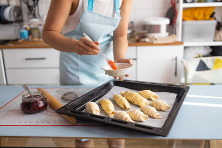 Woman making croissants on a baking sheet in the kitchen.
