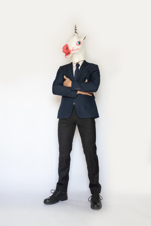 funny businessman wearing a unicorn mask isolated on white background, full body studio shot....