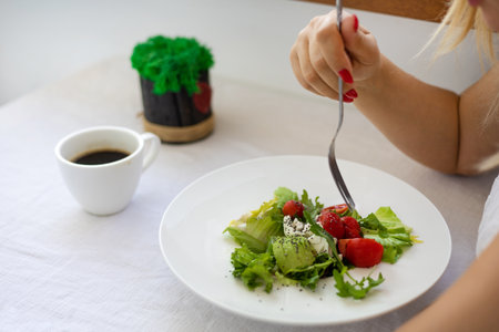 Close-up of a woman eating salad in a restaurant. Healthy food conceptの写真素材