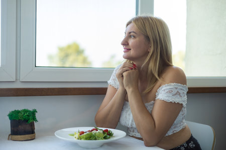 Portrait of a young woman sitting in a cafe and eating saladの写真素材