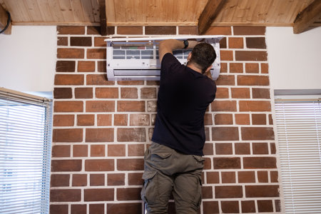 Worker installing air conditioner on the wall in a new houseの写真素材
