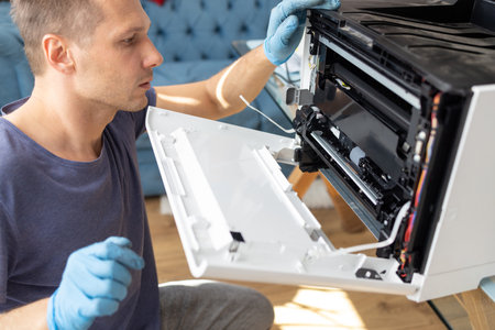 Repairman repairing a broken printer at home. Repair service.の写真素材