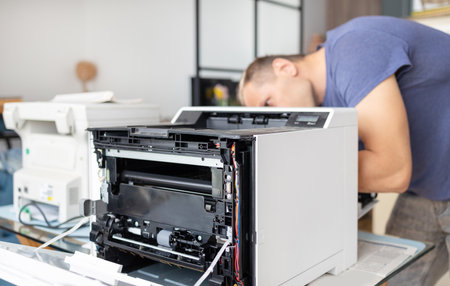 Close-up of a man repairing a photocopier in his office