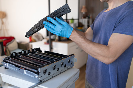 printer repair technician. A male handyman inspects a laser printer before starting repairs in a...