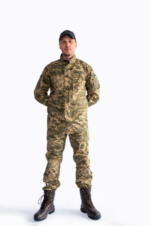 Full length portrait of a young soldier standing with hands on hips against white backgroundの写真素材