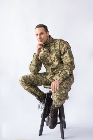 Portrait of a young soldier sitting on a chair against white backgroundの写真素材