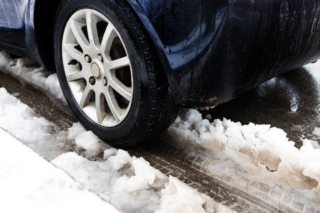 Dirty car tire with snow on the body of the car dirty snow from the road, close-up. Rust and corrosion of cars in the winter outdoors.の写真素材