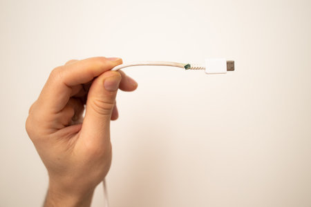 Close up of broken smart phone charger cable on light background