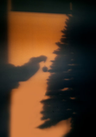 Shadow of hand carefully place retro decorations, creating warm holiday atmosphere.の写真素材