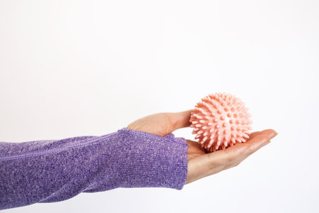 Spiked rubber massage ball in a woman's hand. Ball for recovery and rehabilitation or for relaxation and massage. Fitness equipment. Myofascial release concept.の写真素材
